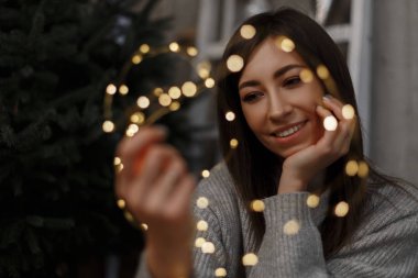 Closeup Noel ışık çelenk elinde tutan hassas bir genç kadın. Güzel kız gülümsüyor. Yeni yıl, yılbaşı, tatil ve kutlama kavramı.