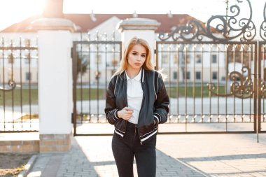 Modaya uygun kot pantolon beyaz gömlek teşkil arka planı beyaz bina vintage gate yakınındaki bir bahar şık ceket modelinde çekici genç kadın. Amerikan şık kız. Moda