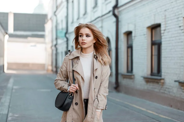 时尚的年轻女子穿着一件白色 T恤的春光外套 在一座旧砖楼的背景下 一个时尚的黑色皮包走在大街上 时尚可爱的欧洲女孩 — 图库照片