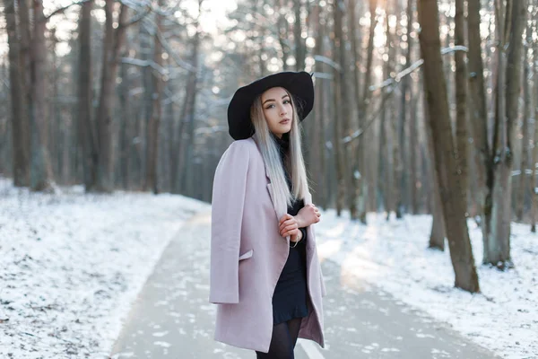 迷人的可爱可爱美丽的年轻女子在时尚温暖迷人的衣服在优雅的帽子是站在路上的雪公园在一个冬天阳光明媚的日子 时尚迷人的现代女孩 — 图库照片