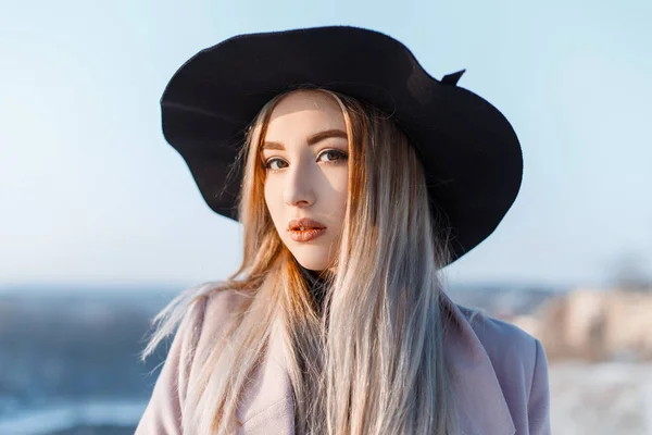 青空にピンクのコートでエレガントな帽子にブロンドの髪 茶色の目と美しいメイクアップと白い肌の若いきれいな女性 素晴らしい官能的な女の子 — ストック写真