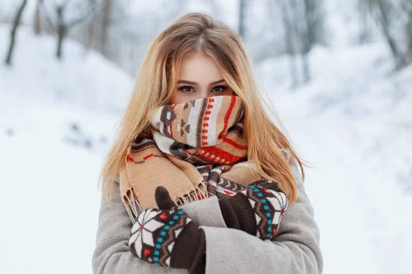 冬雪の公園でヴィンテージ ミトンでスタイリッシュな暖かい灰色のコートで驚くほどの茶色の目で陽気な若い幸せな女 彼女の顔にウール スカーフで陽気なスタイリッシュな女の子 — ストック写真