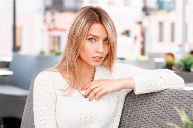 Sevimli çekici genç kadın mavi gözlü çok güzel bir gülümsemen şık beyaz örgü kazak sarışın saçlı açık bir kafede oturuyor. Tatil çekici kız.