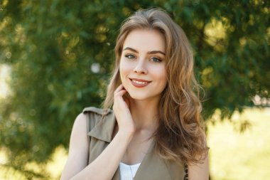 Doğal makyaj bir yeşil ağaç karşı yaz şık giysileri ile sevimli bir gülümseme ile büyüleyici bir kız portresi. Mutlu zarif kız.