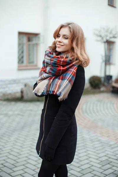 白いモダンな建物に対してファッショナブルなビンテージ格子ウール スカーフ黒手袋でスタイリッシュな冬の暖かいコートにかわいい若い魅力的な女性 笑顔素敵な女の子 — ストック写真