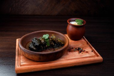 Üzüm lezzetli Dolma yoğurt ile bir restoranda bir ahşap tahta üzerinde bırakır. Ulusal geleneksel çanak. Gürcü mutfağı.
