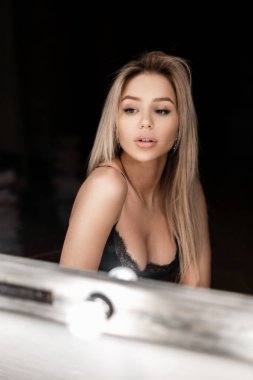 Vintage bir ayna yakınındaki karanlık bir odada bir zarif dantel sütyen muhteşem bir meme ile güzel bir vücudu olan seksi sarışın kadın oturuyor. Modern kız dinlenme kapalı