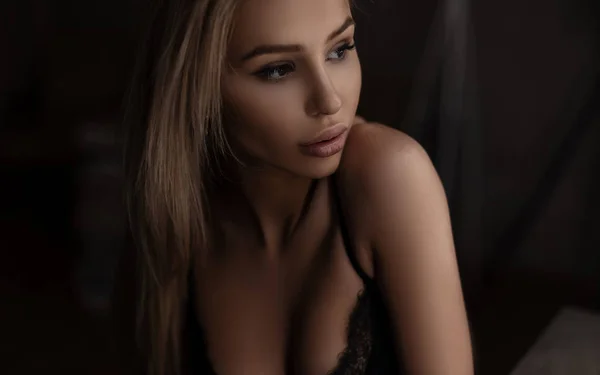 漂亮可爱的年轻女子模型与美丽的乳房在一个别致的胸罩与性感的嘴唇在黑暗的卧室 一个感性的有吸引力的女孩的肖像 — 图库照片
