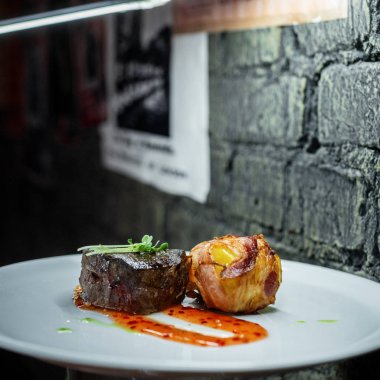 İştah açıcı sulu biftek biftek ile kızarmış domuz pastırması rulo bir restoranda bir tabakta. Yemek vakti.