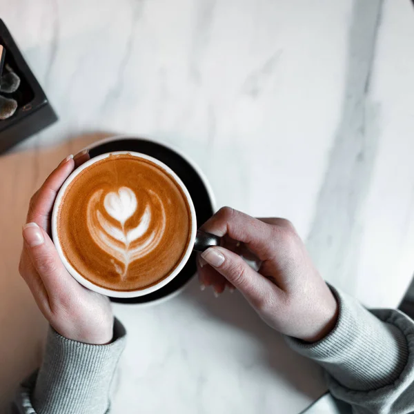 Vrouw houdt een kopje met een heerlijke hete latte in een vintage koffieshop. Koffie gastronomische. Goedemorgen. Van bovenaf bekijken. — Stockfoto