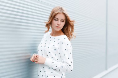 Parlak güneşli bir gün bir Vintage metal duvar yakın şehirde açık havada poz trendy beyaz kazak şık saç modeli ile güzel çekici genç kadın. Sevimli Avrupa kız modeli. Bahar modern tarzı