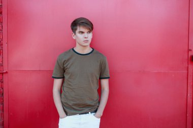 Sıcak bir yaz gününde pembe metal duvar yakın beyaz pantolon bir Vintage yeşil t-shirt şık bir saç modeli ile moda yakışıklı genç adam. Cool Amerikan adam açık havada dinleniyor. Gençlik tarzı.