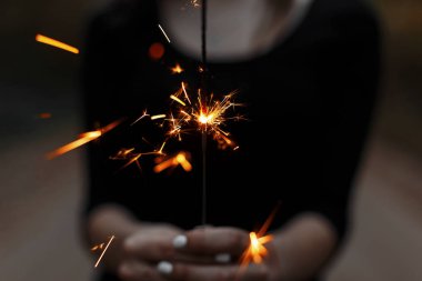 Kadın içinde güzel parlak kutlama maytap karanlık bir arka plan üzerinde eller. Yakın çekim.