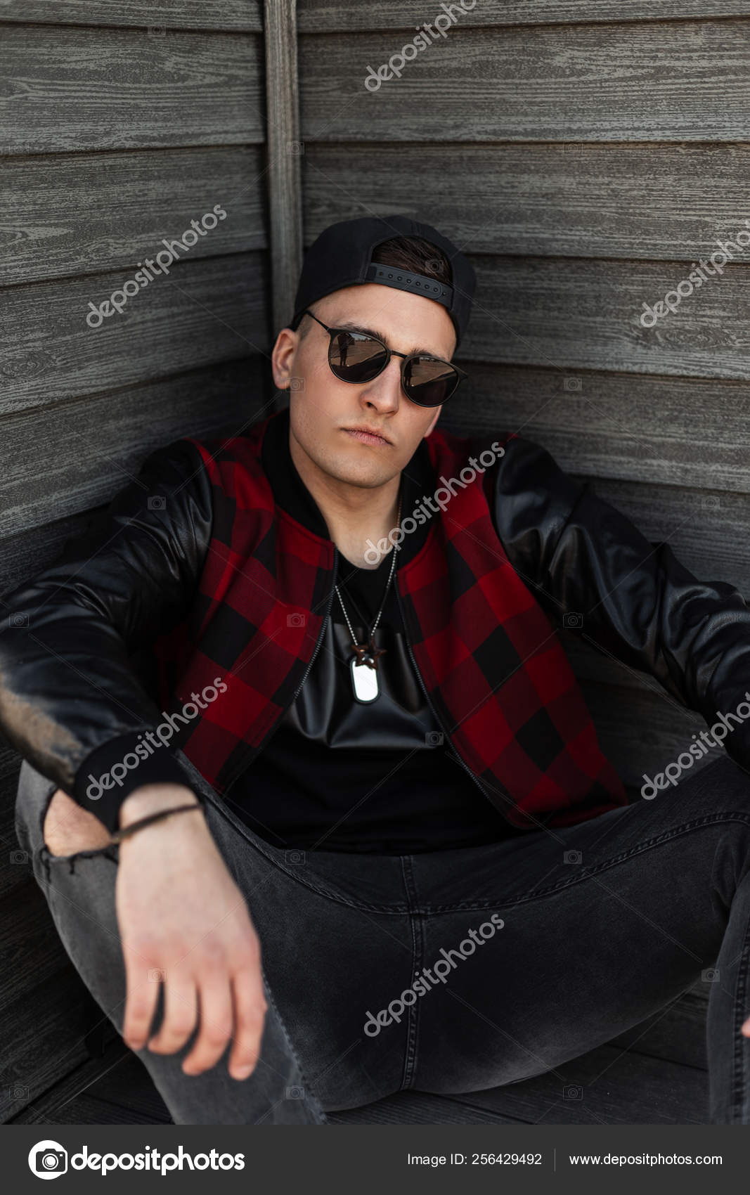 handsome young man wearing sunglasses sitting with bottles of red