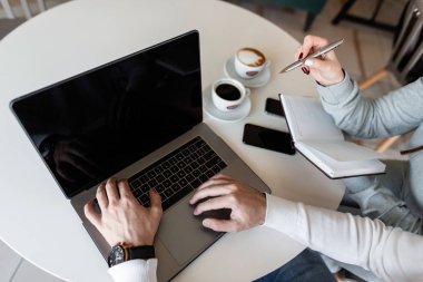 İki başarılı profesyoneller bir erkek ve bir kadın kendi iş projesi için online fikirler arıyoruz. Dizüstü bilgisayarile erkek ellerinin üst te görünümü.