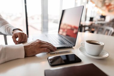 Güneşli bir günde ofisteki masada dizüstü bilgisayarla çalışan genç profesyonel yönetici. Çalışma zamanı.