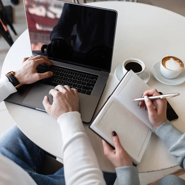 Adam serbest bir dizüstü bilgisayarda notlar alır bir kız yöneticisi yanında bir masada otururken bir dizüstü bilgisayarda yazıyor. İş adamlarıyla işbirliği. Takım çalışması. Close.