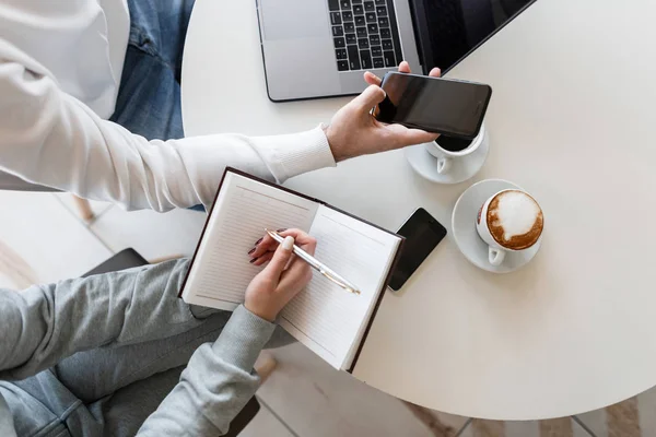 Due giovani imprenditori un uomo e una donna siedono a un tavolo in un ufficio e discutono di un progetto finanziario. Primo piano delle mani femminili con blocco note . — Foto Stock