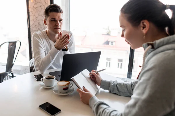 Leader di successo e imprenditore conduce un incontro d'affari informale in un caffè.Giovane donna prende appunti su un blocco note in primo piano. Concetto di impresa e imprenditorialità. Lavoro di squadra . — Foto Stock