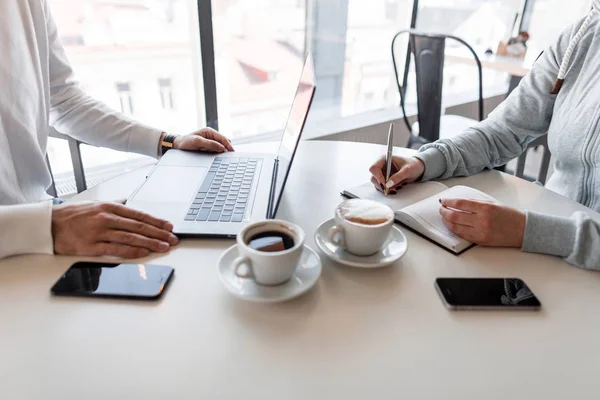 Il manager umano intervista un candidato in un ambiente informale seduto in un caffè. Donna freelance ascolta un uomo e scrive in un quaderno . — Foto Stock