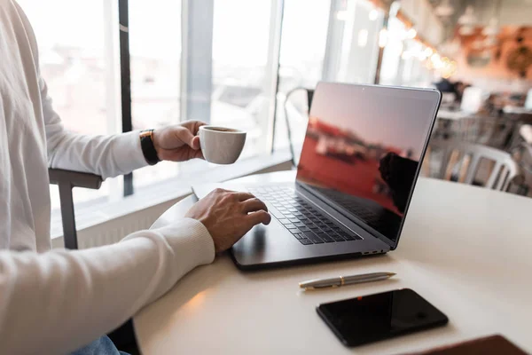 Young blogger uses a laptop for work. Business man working on a computer and drinking coffee. — Stock Photo, Image