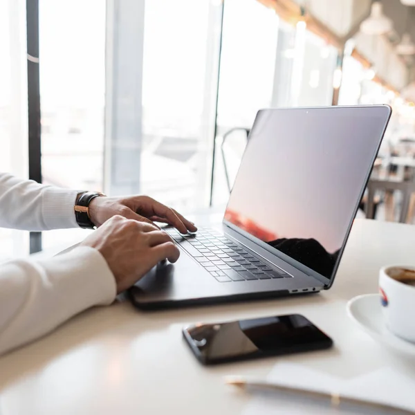 Homem freelancer bem sucedido trabalhando em laptop no escritório em um dia ensolarado de verão. Fechar as mãos masculinas, uma chávena de americano e um telemóvel. Tempo de trabalho . — Fotografia de Stock