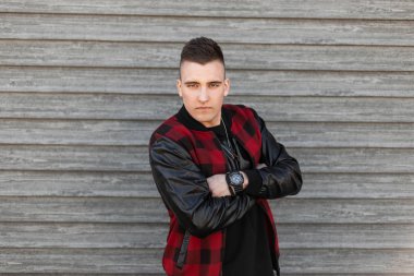 Bir saat ile bir t-shirt şık bir saç modeli ile bir vintage ekose ceket çekici genç adam bir bahar gününde ahşap bir duvar yakınında poz lar. Moda ciddi adam hafta sonu zevk.