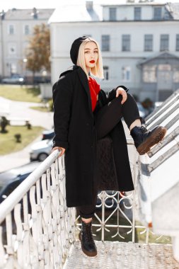Deri ayakkabı pantolon şık bir kırmızı gömlek siyah bir ceket bir Vintage Beret kırmızı dudaklar ile çekici sevimli kadın sarışın şehirde açık havada dinleniyor. Moda kız moda modeli. Retro tarzı.