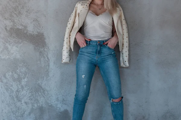 Das schlanke junge Model posiert in modischer Jugendkleidung an einer grauen Wand. neue Frühjahrskollektion stilvoller Damenbekleidung. — Stockfoto