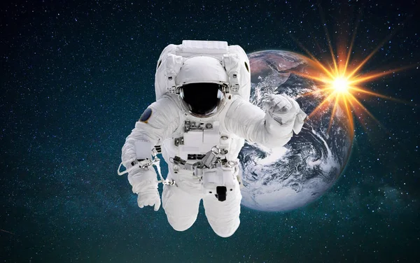 Homem do espaço no espaço voa perto do planeta Terra ao pôr-do-sol. Astronauta realiza missão espacial contra as estrelas — Fotografia de Stock
