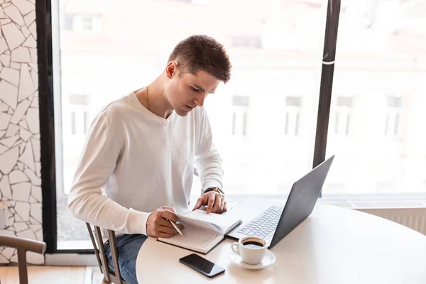 Profesionální mladý obchodník vytváří poznámky v poznámkovém bloku a pracuje v přenosném počítači na internetu s novým finančním projektem. Nezávislý člověk pracuje vzdáleně. — Stock fotografie