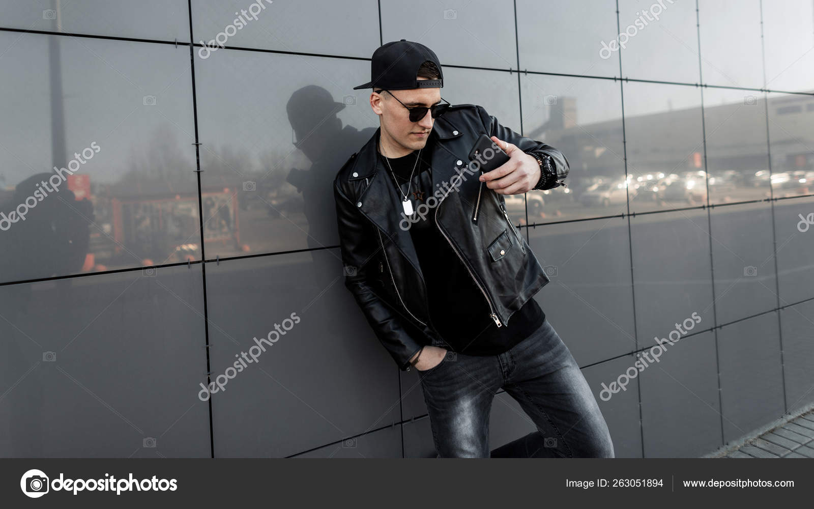 American young man hipster in a black leather jacket in a baseball