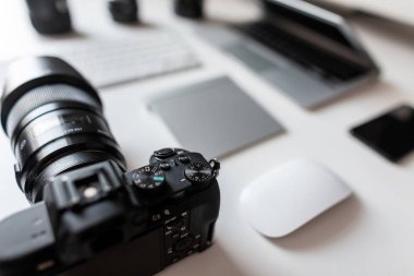 Profesyonel bir fotoğrafçının işyeri. Ön planda siyah modern bir kamera var. Fotoğraf işleme tesisleri grubu.
