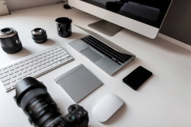 Bilgisayarlı, dizüstü bilgisayarlı, modern profesyonel kameralı, dizüstü bilgisayarlı ve bilgisayarlı bir klavyeli bir fareyle Al Desktop 'un beyaz masaüstü. Şık bir iş yeri.