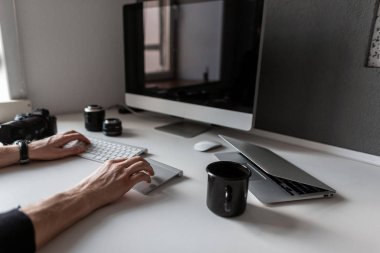 Bilgisayarda çalışan serbest çalışan adam. Kahve, kamera, dizüstü bilgisayar, klavye ve lenslerle yaratıcı masaüstü.