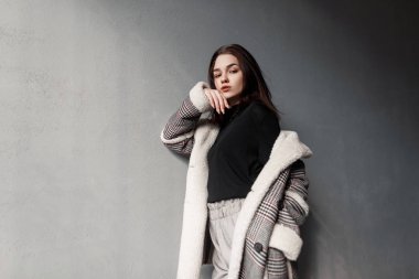 Gri moda pantolon açık havada beton duvar yakınında dinlenme bir vintage damalı ceket siyah bir t-shirt Pretty şehvetli genç esmer kadın. Güzel zarif kız modeli. Bahar stili.