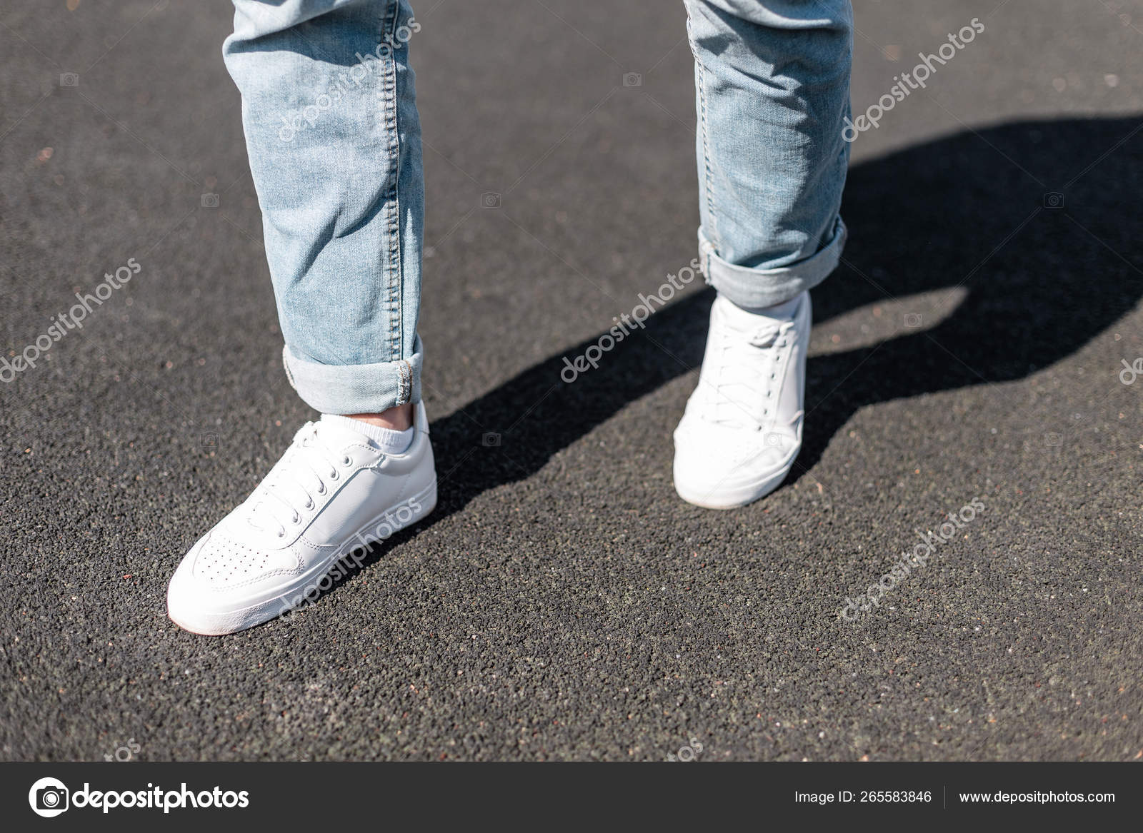 Stylish young man stands on an asphalt road in leather white