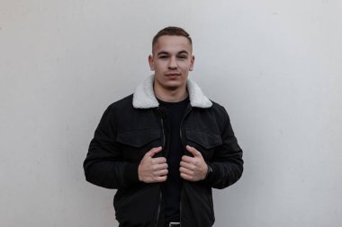 Şık bir saç modeli ile şık bir t-shirt bir vintage siyah ceket joyful çekici genç adam kapalı duvara yakın ayakta poz. Şehirli modern adam. Şık erkek giyim.