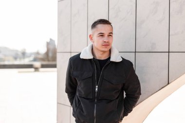 Modaya uygun siyah mevsimlik giysiler içinde Nice modern genç adam parlak bir bahar gününde açık havada bir vintage binanın yakınında duran rahatlatır. Avrupalı yakışıklı erkek modeli dinleniyor. Güzel şık insanlar.