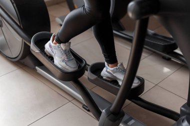 Beyaz spor ayakkabılı kadın bacakları bir spor stüdyosunun step simülatöründe çalışır. Spor salonunda ki antrenmanda bir kadın. Close.