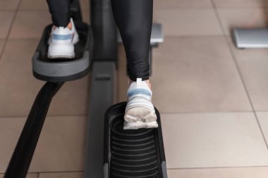 Bir spor salonunda modern bir step simülatörü beyaz spor spor spor ayakkabı kadın bacaklar Closeup. Kız egzersiz spor sınıfı yok. Geri görünüm.