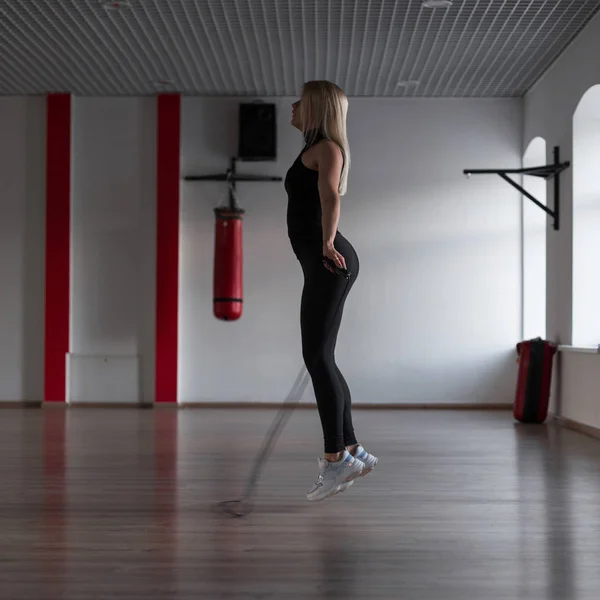 Piękna Szczupła blondynka robi ćwiczenia z skakania liny w siłowni. Dziewczyna sportowa w skoku. Zdrowy styl życia. — Zdjęcie stockowe