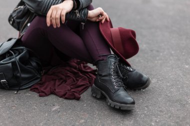 Şatafatlı, mor şapkalı, deri pantolonlu, şık siyah çizmeli genç bir kadın. Şık kadın başlığı ve ayakkabıları. Retro tarzı. Kadın bacaklarına yakın çekim.