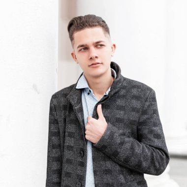 Beyaz modern bir binanın yakınındaki bir şehirde poz şık bir saç modeli ile şık bir gömlek klasik ekose ceket çekici genç adam. Sokaktaki yakışıklı adam. İş tarzı.