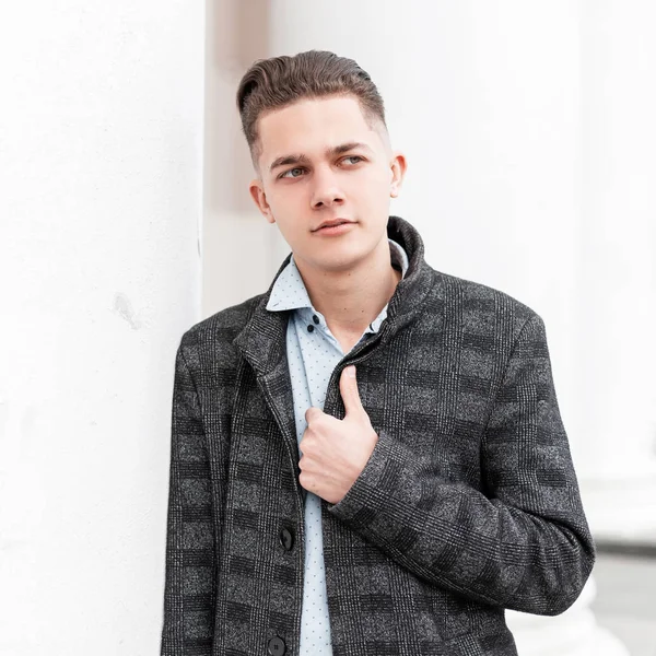 Vonzó fiatalember egy klasszikus kockás kabát stílusos ing divatos frizura pózol a város közelében egy fehér, modern épület. Jóképű fickó az utcán. Üzleti stílus. — Stock Fotó