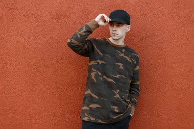 Şehir açık havada pantone renk duvar yakınında poz kot bir vintage yeşil askeri gömlek şık bir kap şık yakışıklı genç adam. Sevimli moda adam modeli. Gençlik sokak stili. Erkek giyim