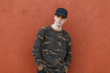 Şık siyah şapkalı şık siyah bir genç adam kot pantolon bir vintage bina pantone renk yakınında şehirde poz 2019. Amerikan havalı erkek modeli. Trendy erkek giyim.