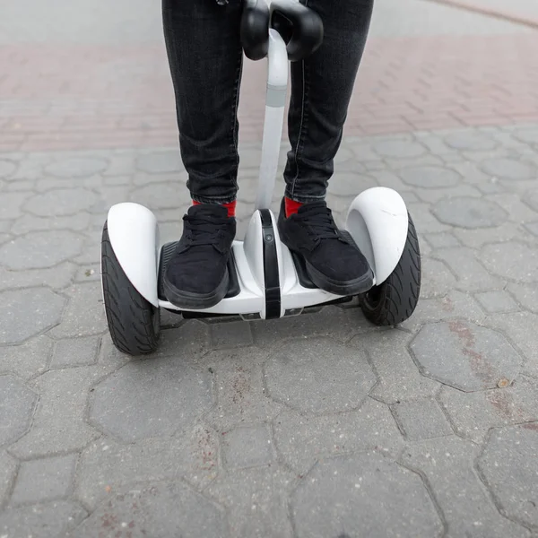 Closeup of male legs in stylish jeans in trendy sneakers  on a gyroscope. Guy rides on a white hoverboard. Modern technologies. Leisure. — Stock Photo, Image