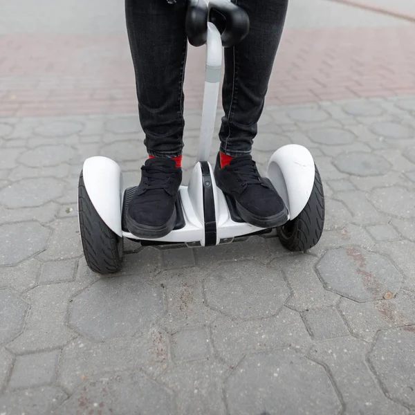 Nahaufnahme von Männerbeinen in stylischen Jeans in trendigen Turnschuhen auf einem Kreisel. Mann fährt auf einem weißen Hoverboard. moderne Technologien. Freizeit. — Stockfoto