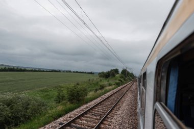 Bulutlu bir günde trenin penceresinden görüntüle. Vagonlar ve demiryolu üzerinde görünümü.
